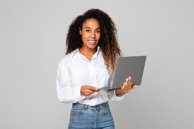 Afro-Amerikaanse vrouw met een laptop die door moderne websites surft studio