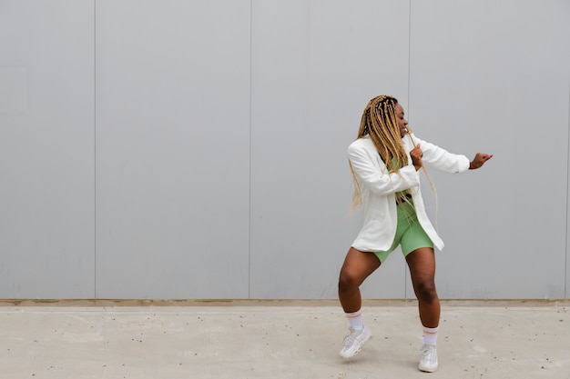 Afro-Amerikaanse vrouw met lange blonde vlechten dansen op straat Kopieer ruimte Stedelijk dansen