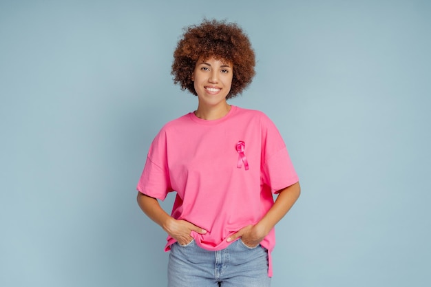 Foto afro-amerikaanse vrouw met roze lint geïsoleerd op blauwe achtergrond borstkanker bewustzijn maand