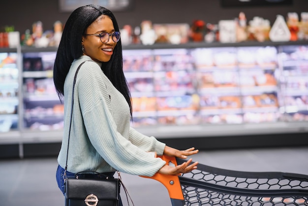 Afro-Amerikaanse vrouw met winkelwagentje in de supermarktwinkel