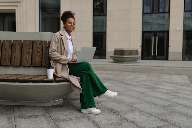 Afro-Amerikaanse vrouw van middelbare leeftijd die buiten aan laptop werkt