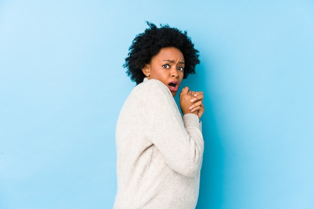 Afro-Amerikaanse vrouw van middelbare leeftijd tegen een blauwe achtergrond geïsoleerd bang en bang.