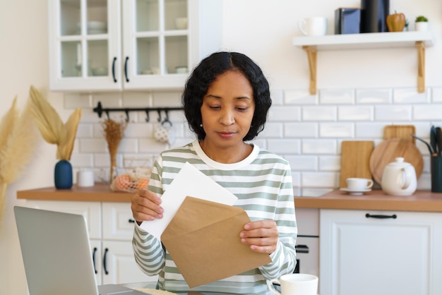 Foto afro-amerikaanse vrouw verzendt brief die correspondentie voorbereidt voor het sluiten van de envelop voor postbezorging