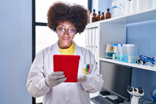 Afro-Amerikaanse vrouwelijke wetenschapper die touchpad gebruikt die in het laboratorium werkt