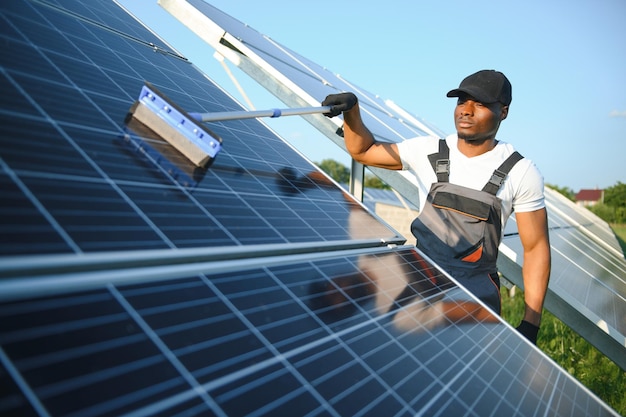 Afro-Amerikaanse werknemer die zonnepaneel in zonne-energiecentrale schoonmaakt