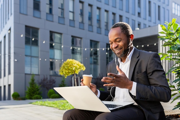 Afro-Amerikaanse zakenman buiten kantoorgebouw in gesprek met collega's op afstand baas in het bedrijfsleven