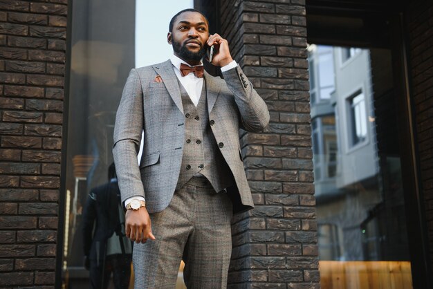 Afro-Amerikaanse zakenman draagt een pak staande in een zakelijke omgeving buitenshuis