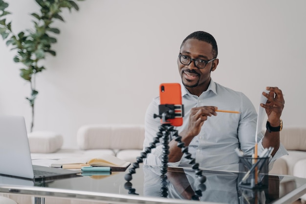 Afro-Amerikaanse zakenman geeft online presentatie voor team via videogesprek met smartphone