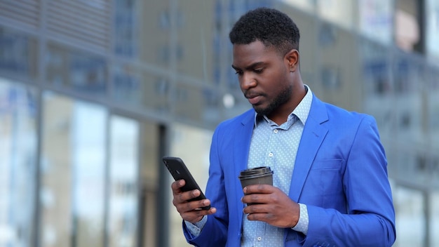 Afro-Amerikaanse zakenman leest artikel op telefoonscherm