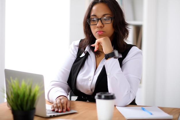 Afro-Amerikaanse zakenvrouw is bezig met laptop op kantoor