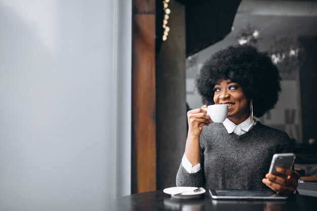 Afro-Amerikaanse zakenvrouw met tablet en koffie in een café