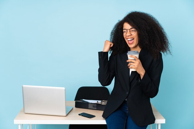 Afro-Amerikaanse zakenvrouw werken op haar werkplek een overwinning vieren