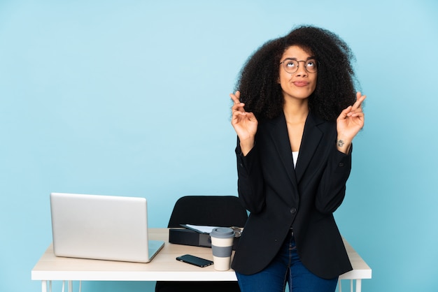 Afro-Amerikaanse zakenvrouw werken op haar werkplek met vingers kruisen en het beste wensen