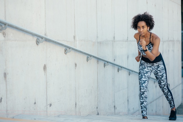 Photo afro athletic woman running and doing exercise outdoors.