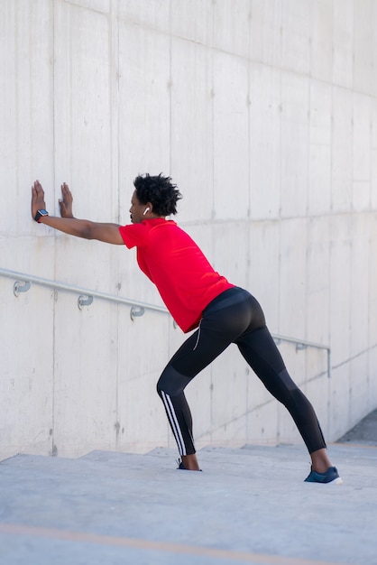 Afro atletische man die zich uitstrekt en opwarmt voordat hij buiten gaat trainen. Sport en een gezonde levensstijl.