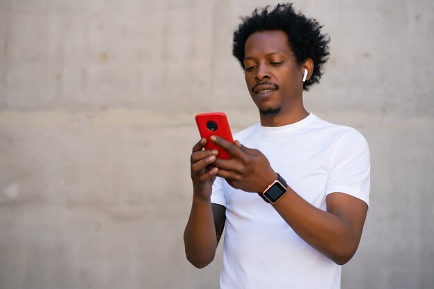 Afro atletische man met behulp van zijn mobiele telefoon en ontspannen na de training buitenshuis