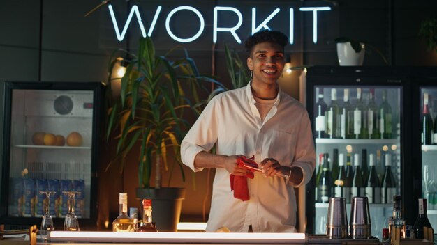 Afro barman cleaning glasses working at bar counter friendly waiter waving hand