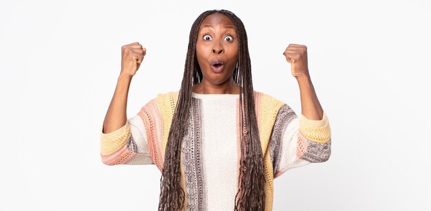 Afro black adult woman celebrating an unbelievable success like a winner, looking excited and happy saying take that!