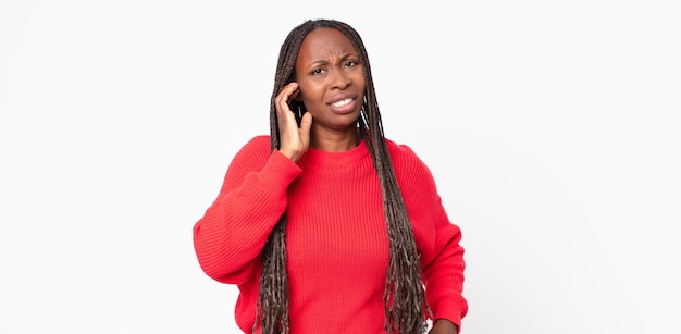 Afro black adult woman feeling stressed, frustrated and tired, rubbing painful neck, with a worried, troubled look