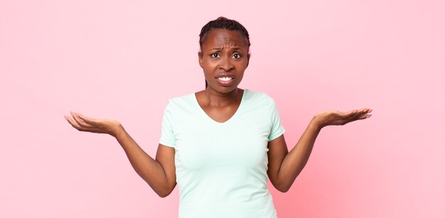 Afro black adult woman looking puzzled, confused and stressed, wondering between different options, feeling uncertain