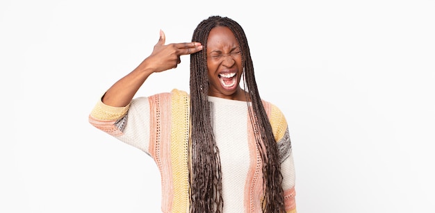 Afro black adult woman looking unhappy and stressed, suicide gesture making gun sign with hand, pointing to head