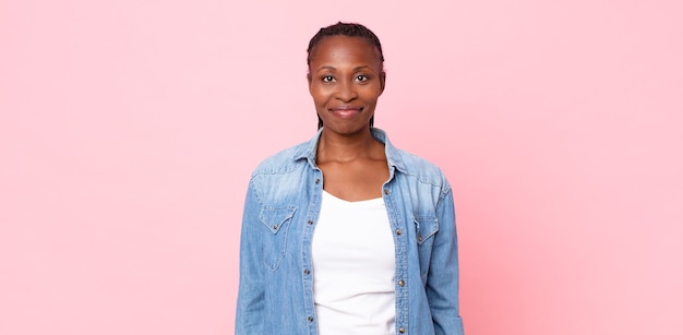 Afro black adult woman smiling positively and confidently, looking satisfied, friendly and happy