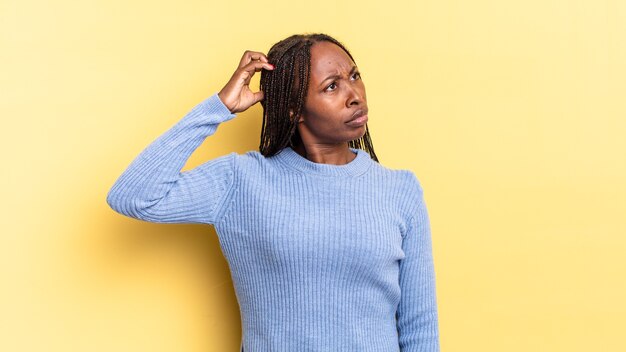 Afro black pretty woman feeling puzzled and confused, scratching head and looking to the side