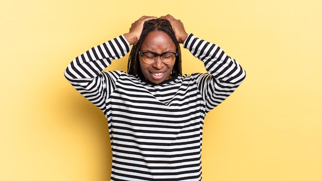 Afro black pretty woman feeling stressed and frustrated, raising hands to head, feeling tired, unhappy and with migraine