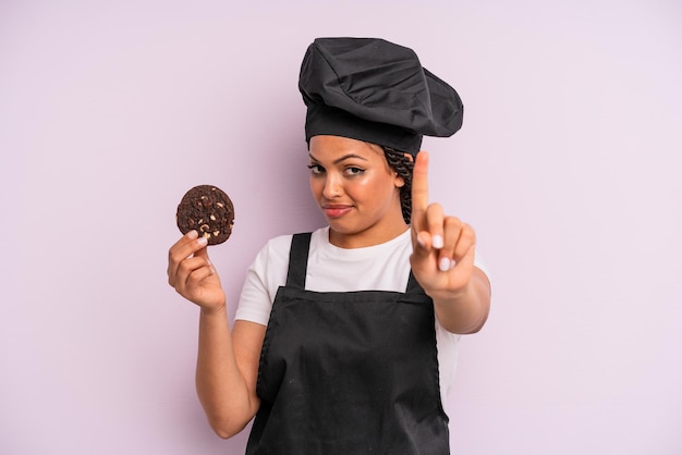 Afro black woman chef with braids and making a cookie