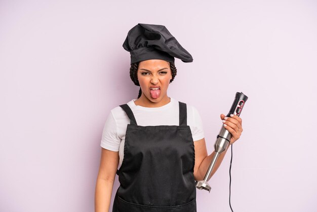 Afro black woman feeling disgusted and irritated and tongue out. chef with hand blender