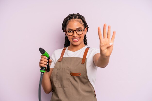 Afro black woman smiling and looking friendly, showing number four. gardener hose concept