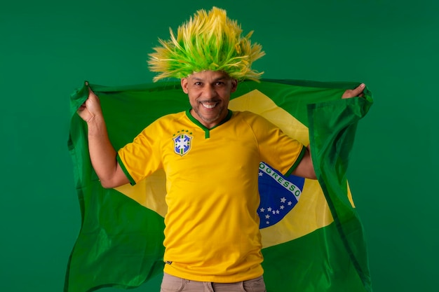 Afro-Braziliaanse man-supporter van het Braziliaanse voetbalteam in de 2022-beker met de vlag van Brazilië en met een gezichtsgezicht