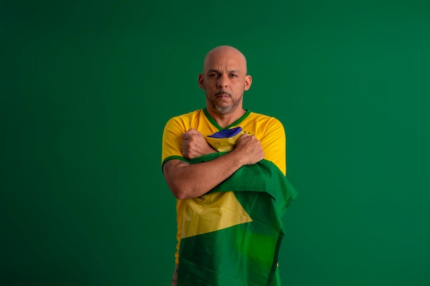 Afro-Braziliaanse man-supporter van het Braziliaanse voetbalteam in de 2022-beker met de vlag van Brazilië en met gezichtsuitdrukkingen