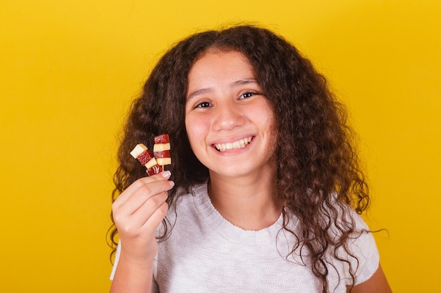 Афро-бразильская латиноамериканская кудрявая девушка улыбается, держа сыр и гуаву на шпажках ромео и джульетта сладко вкусно