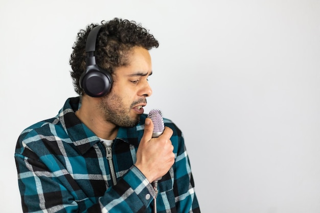 Afro-Brazilian man dressed in checkered shirt singing into a condenser microphone