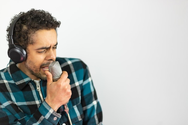 Afro-Brazilian man dressed in checkered shirt singing into a condenser microphone