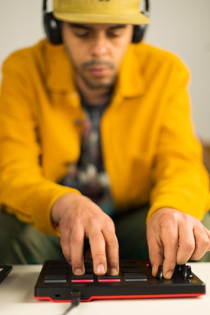 Afro-brazilian man making beats from his sofa at the coffee table with an MPD MIDI controller