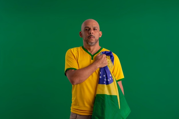 Afro brazilian man supporter of the brazilian football team in\
the 2022 cup with the flag of brazil and with facial\
expressions