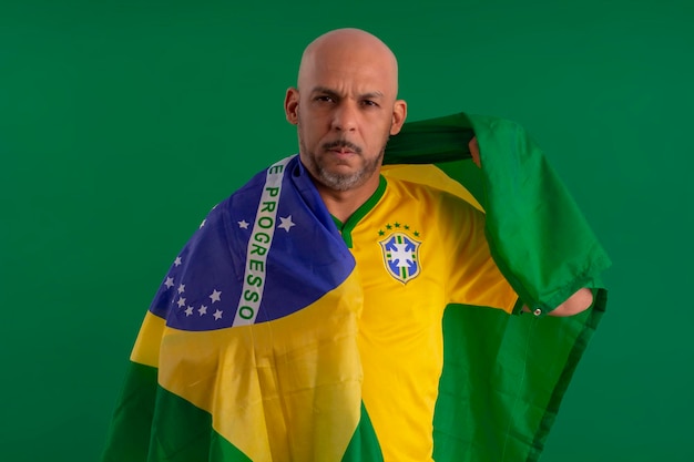 Afro Brazilian man supporter of the Brazilian football team in the 2022 cup with the flag of Brazil and with a facial face