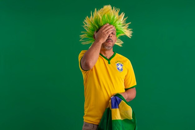 Foto uomo afro brasiliano sostenitore della squadra di calcio brasiliana nella coppa del 2022 con la bandiera del brasile e con una faccia facciale