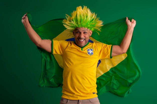 Photo afro brazilian man supporter of the brazilian football team in the 2022 cup with the flag of brazil and with a facial face