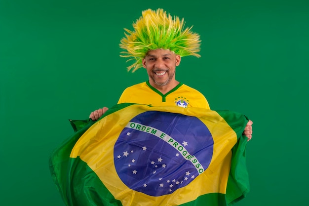 Afro brazilian man supporter of the brazilian football team in\
the 2022 cup with the flag of brazil and with a facial face