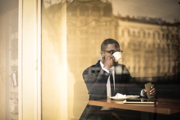 Uomo d'affari di afro che mangia un caffè