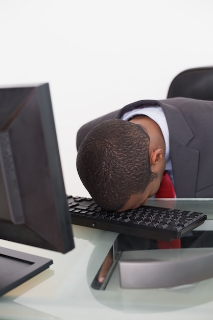 Afro businessman resting head on keyboard in office