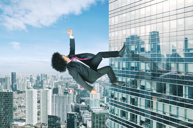 Afro businessman running upward on a skyscraper