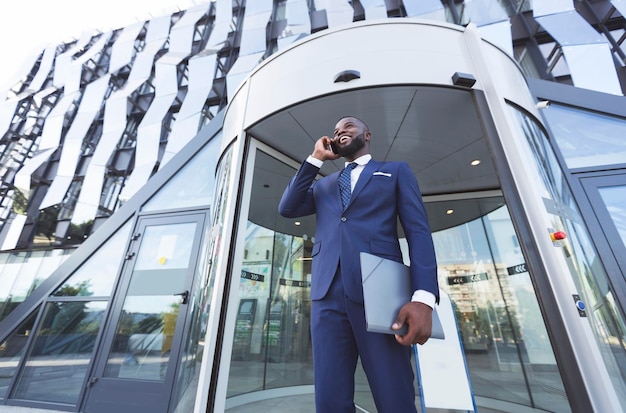 Foto imprenditore afro parlando al telefono contro l'ingresso dell'edificio per uffici