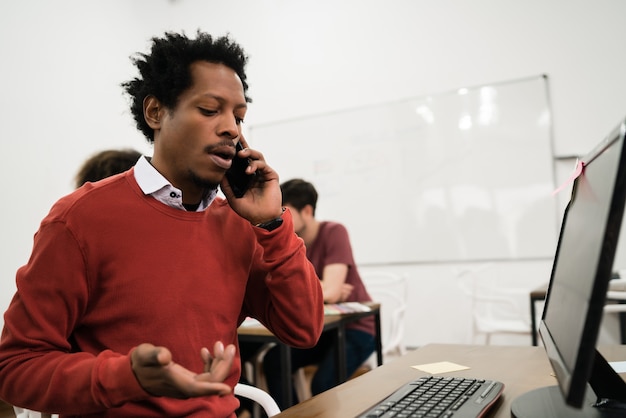 Afro businessman talking on the phone and working at his workplace. Business concept.