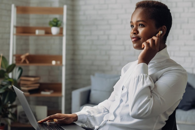 아프리카 경제인은 노트북과 함께 본 의자에 앉아 사무실에서 제쳐두고 찾고 있습니다. 사업가 초상화입니다. 아프리카 계 미국인 소녀입니다. 측면보기.