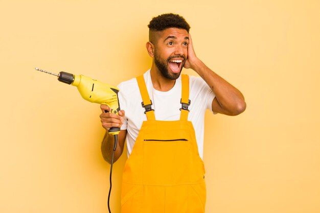 Afro cool man feeling happy excited and surprised handyman and drill concept