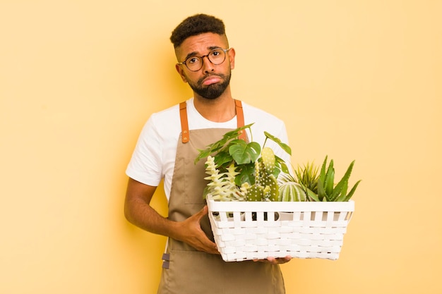 Afro cool man feeling sad and whiney with an unhappy look and crying gardener and plant concept